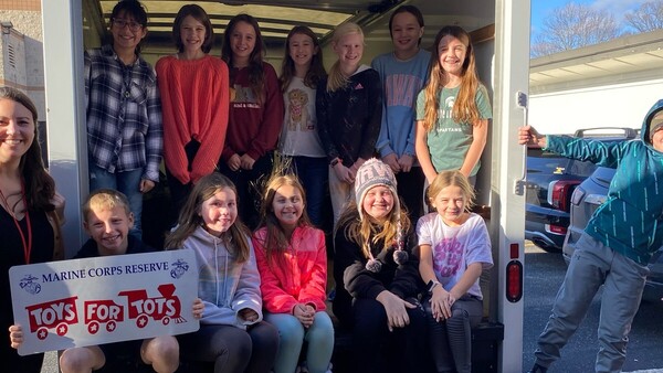 Students sitting inside the bed of the Toys for Tots collection truck.