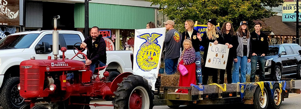Lowell FFA students ride down Main Street on their float led by their advisor, Kevin Nugent, driving a Farmall Tractor.