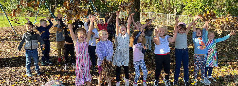 Elementary students playing in the fall leaves.